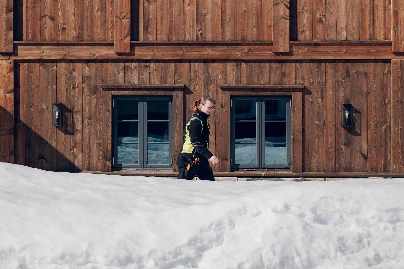 Elektriker Trine Tjørhom går foran en hytte i snøværet.