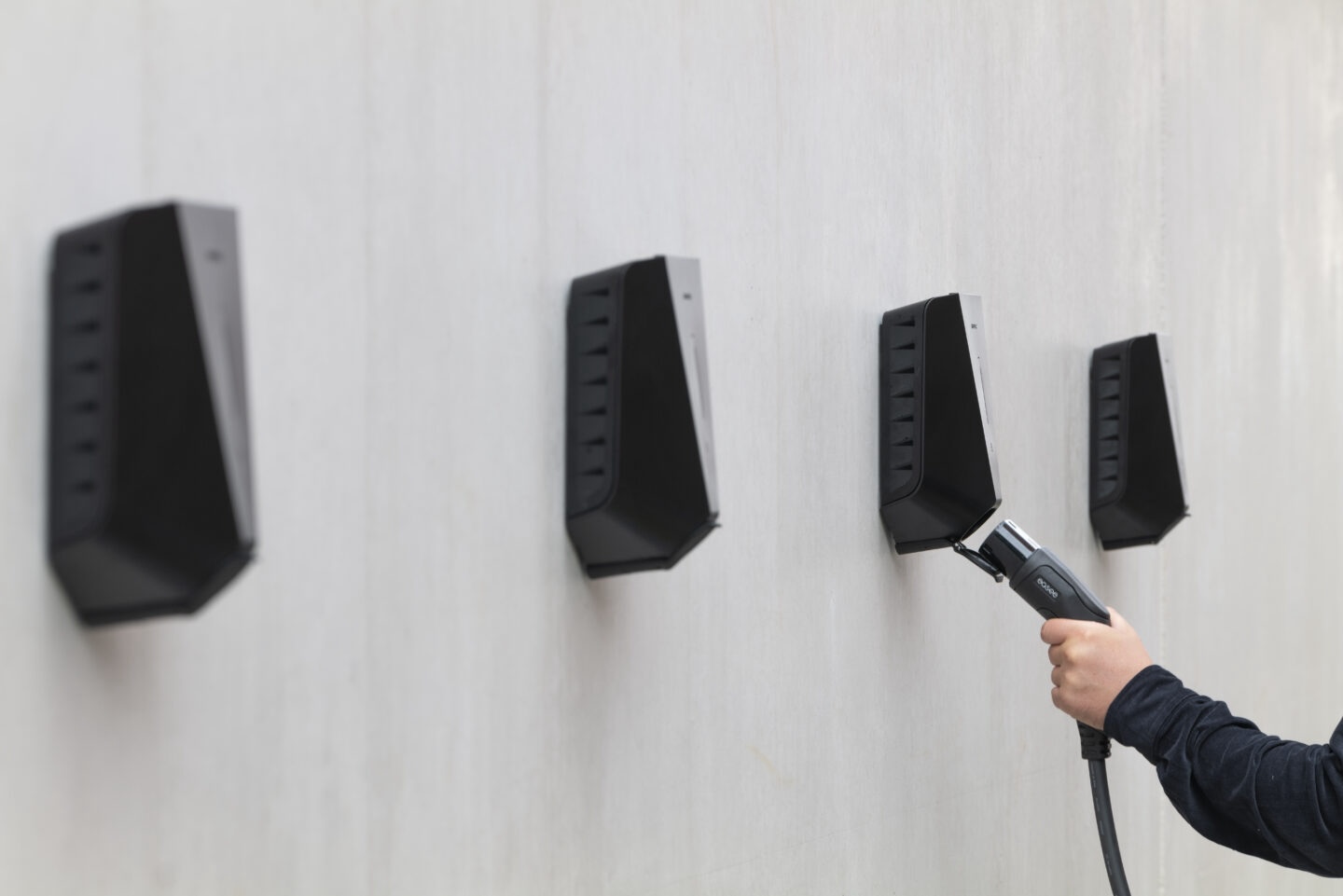 Four black Easee EV chargers mounted on concrete wall