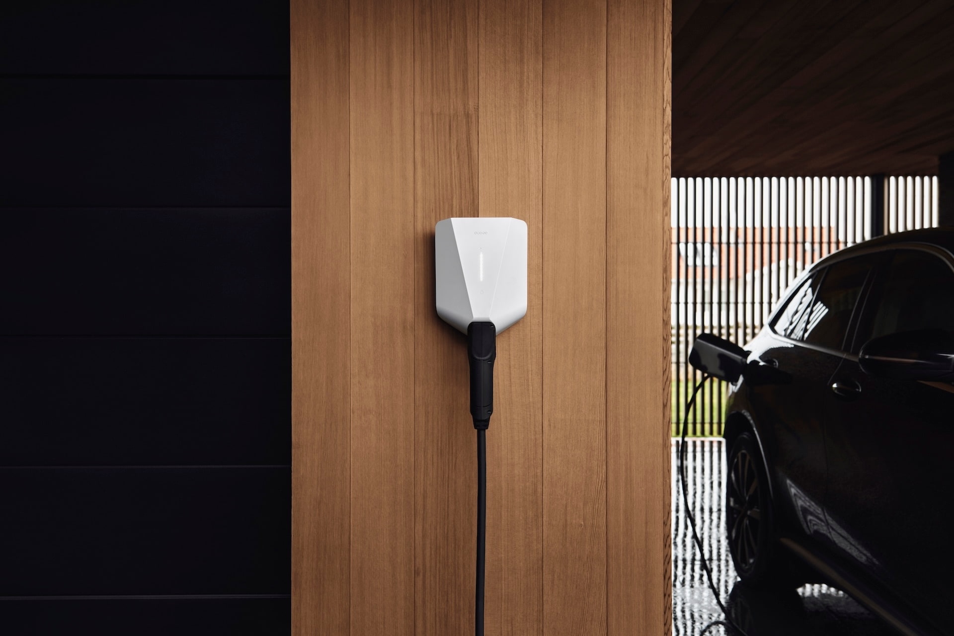 A white, smart EV charger on a wooden wall