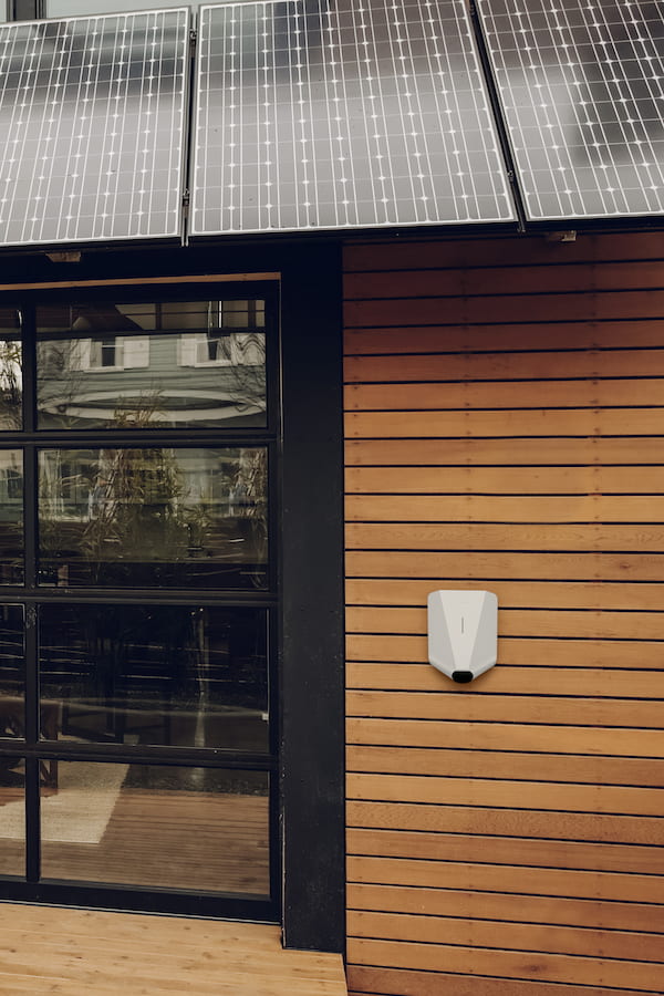 EV charger on wooden wall with solar panels on roof