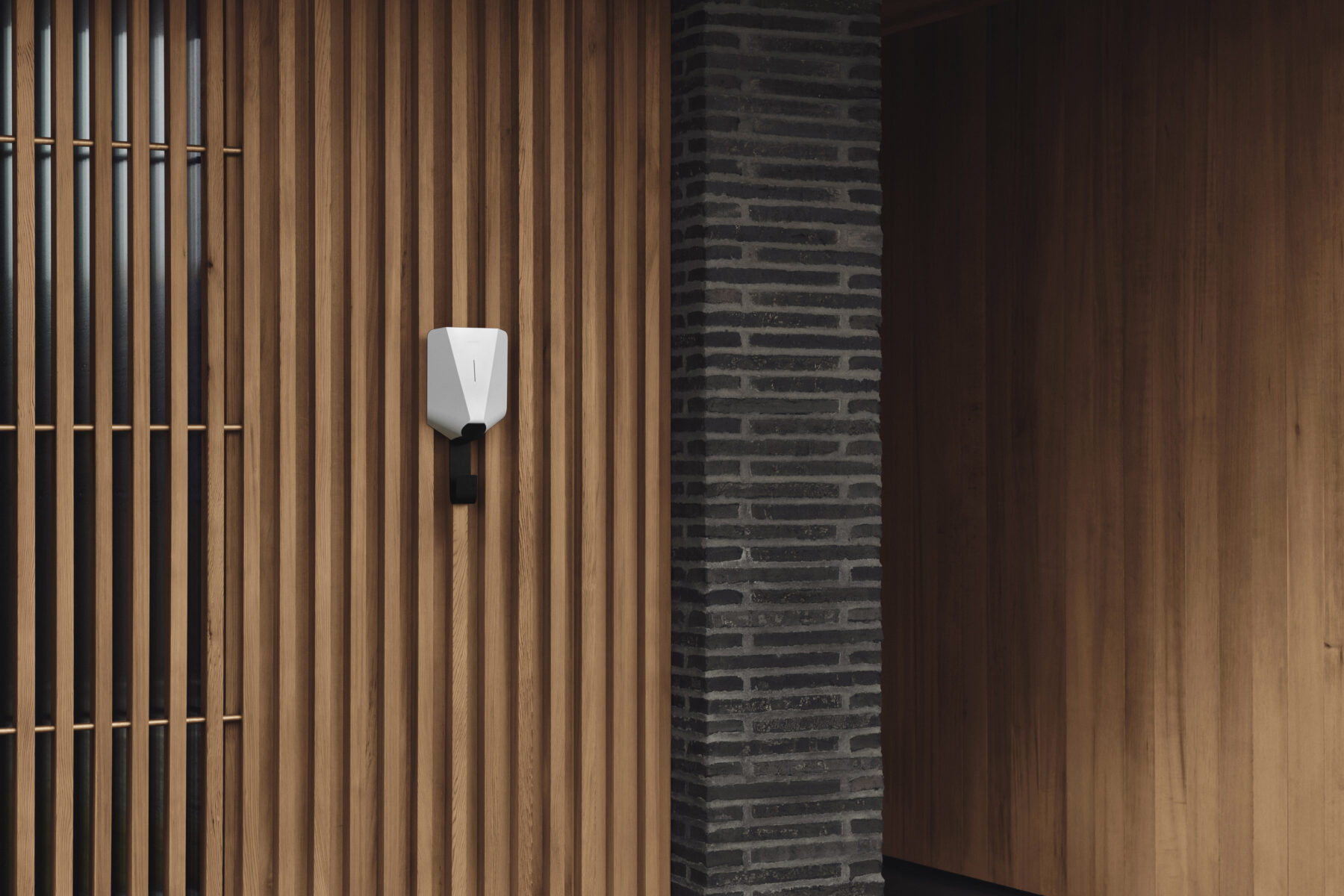 A white Easee EV charger mounted on a wooden wall with a Easee Mount underneath