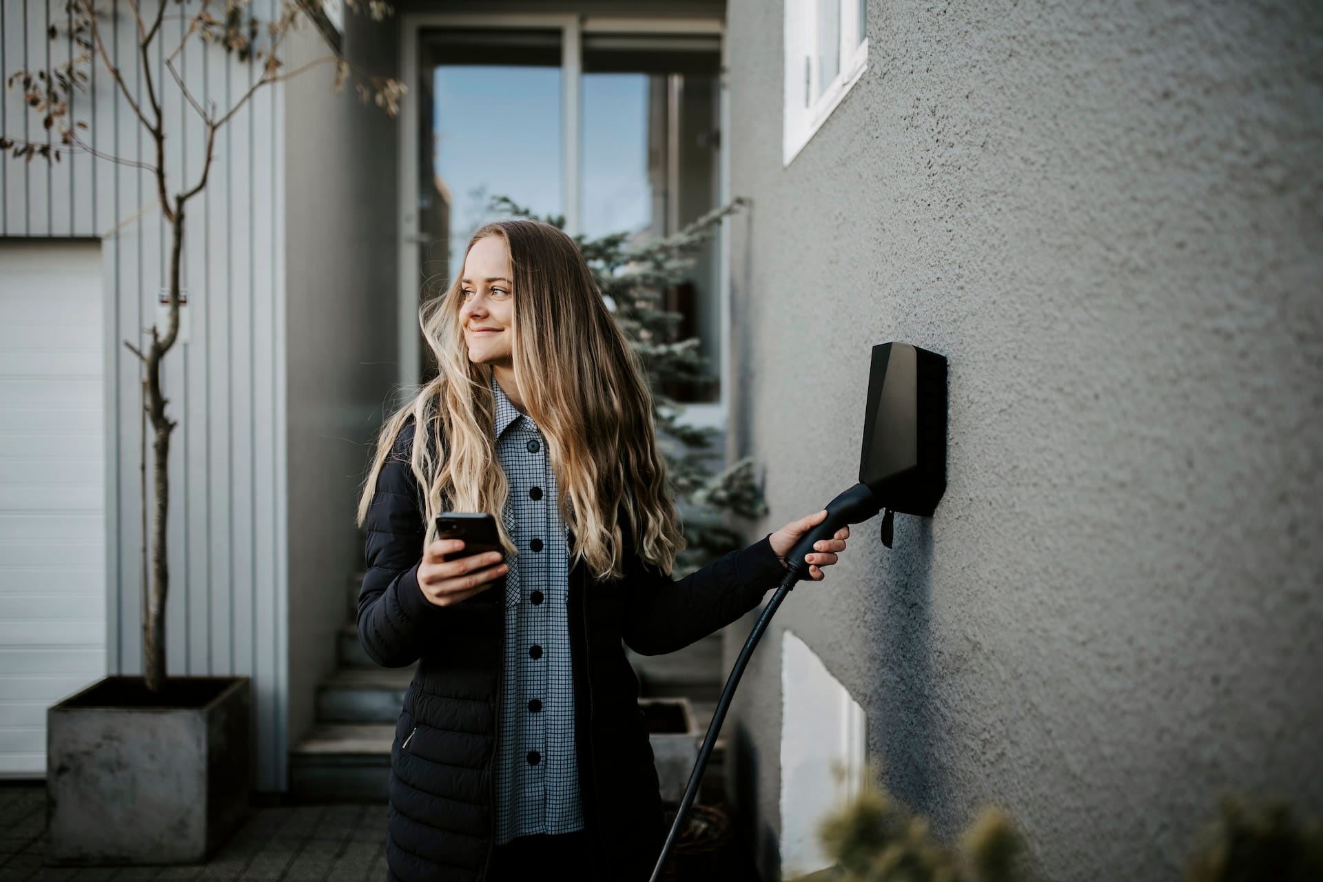 Woman charging her electric car with an Easee charger on a concrete wall