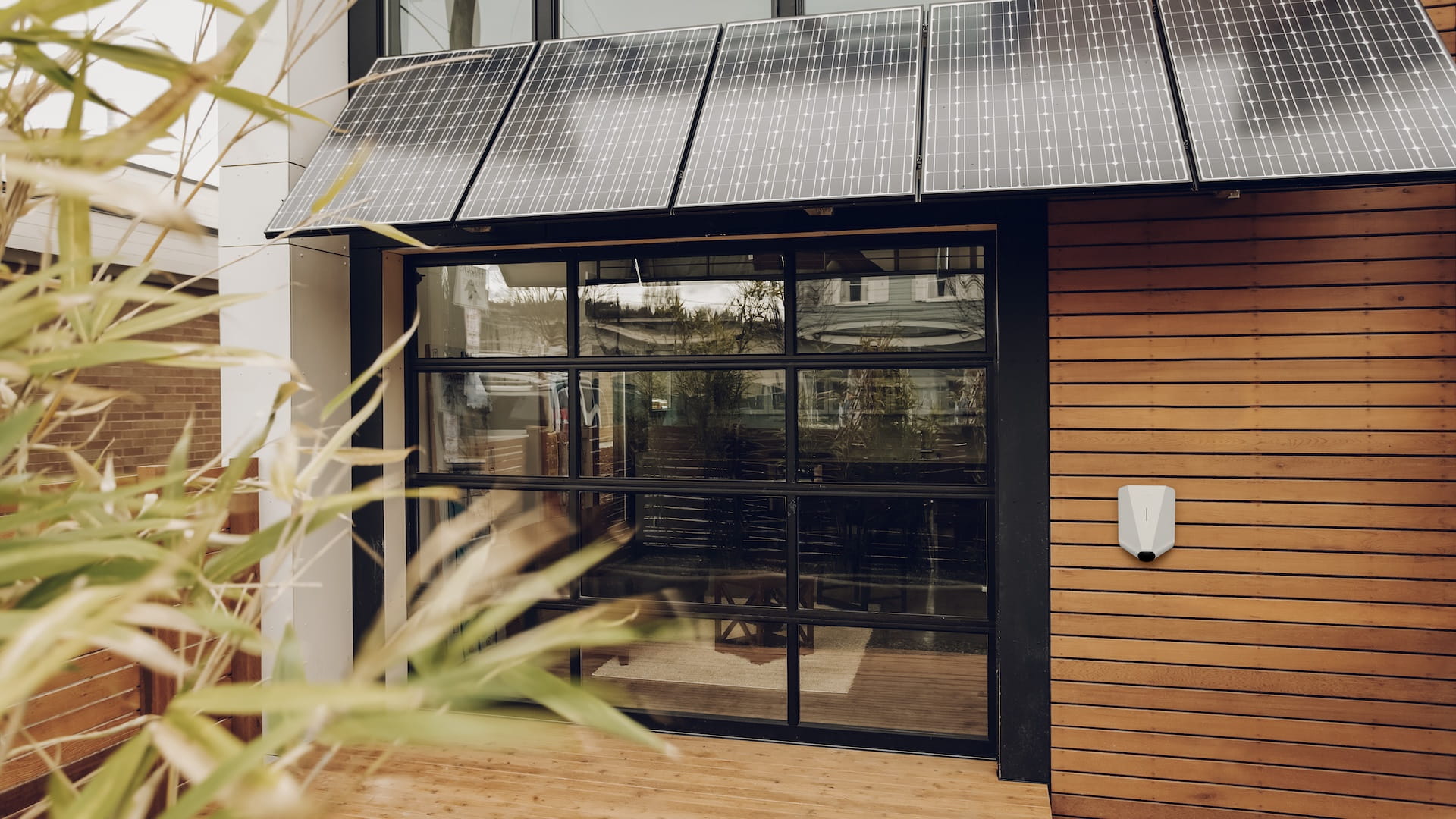 White Easee electric car charger mounted on a housing with a solar panel
