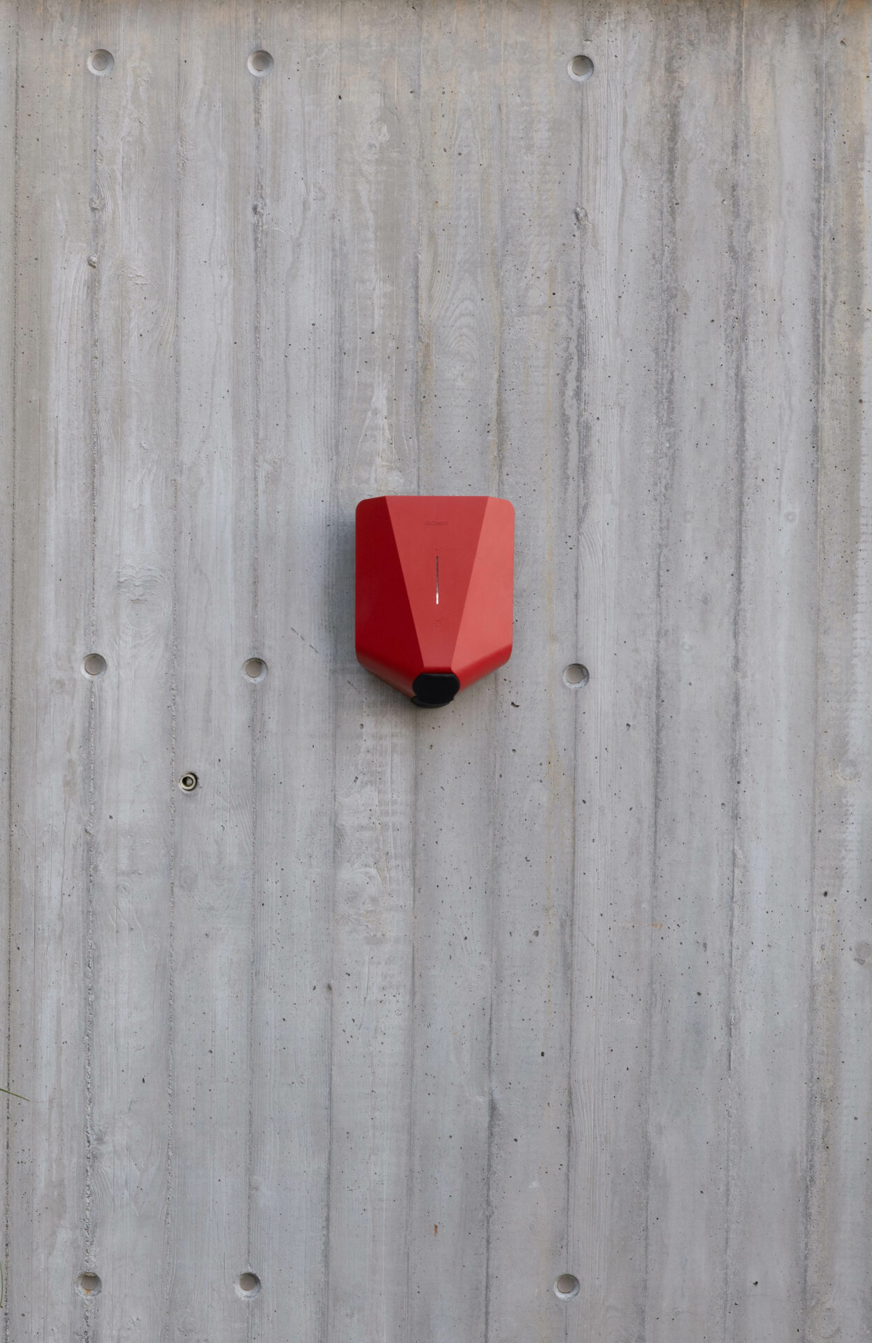 Red EV charger on a concrete wall
