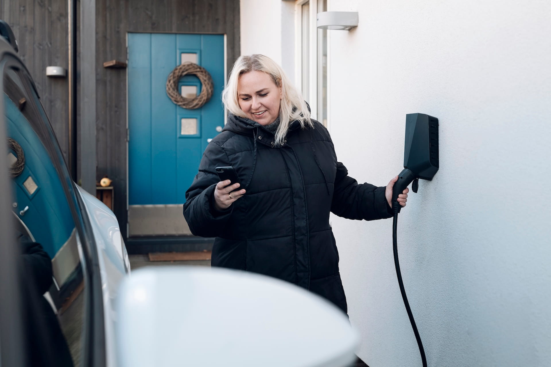 Dame lader elbilen sin og styrer elbilladeren med en app