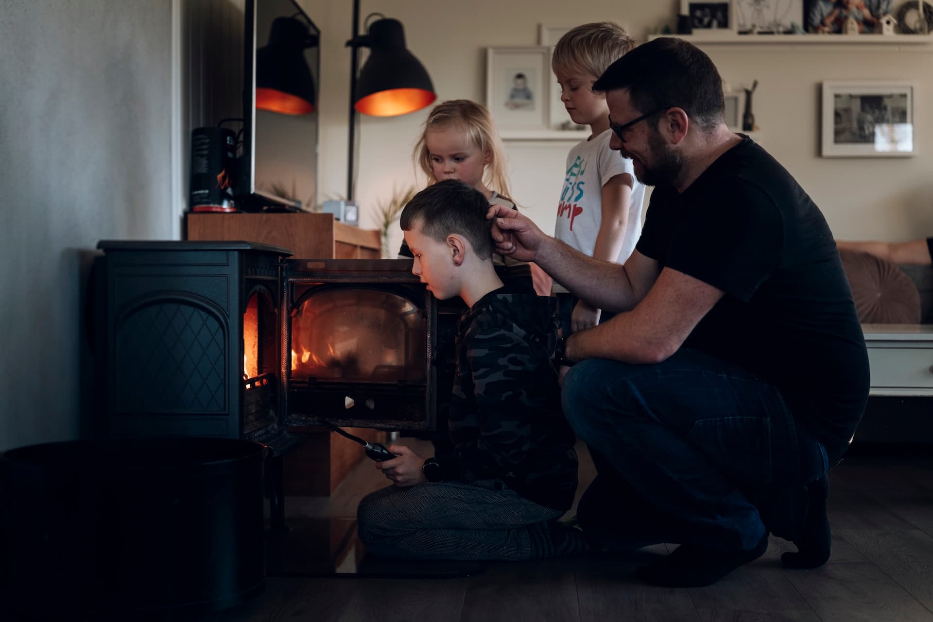 Familiefar med tre barn fyrer i peisen