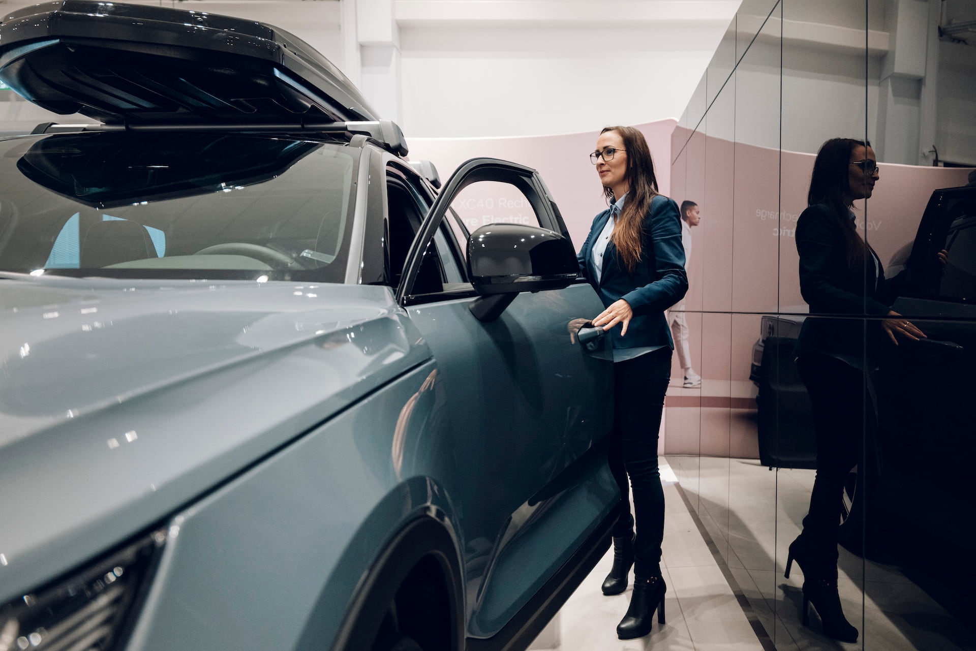 Kvinne åpner døren på en elbil i et bilutstillingslokale