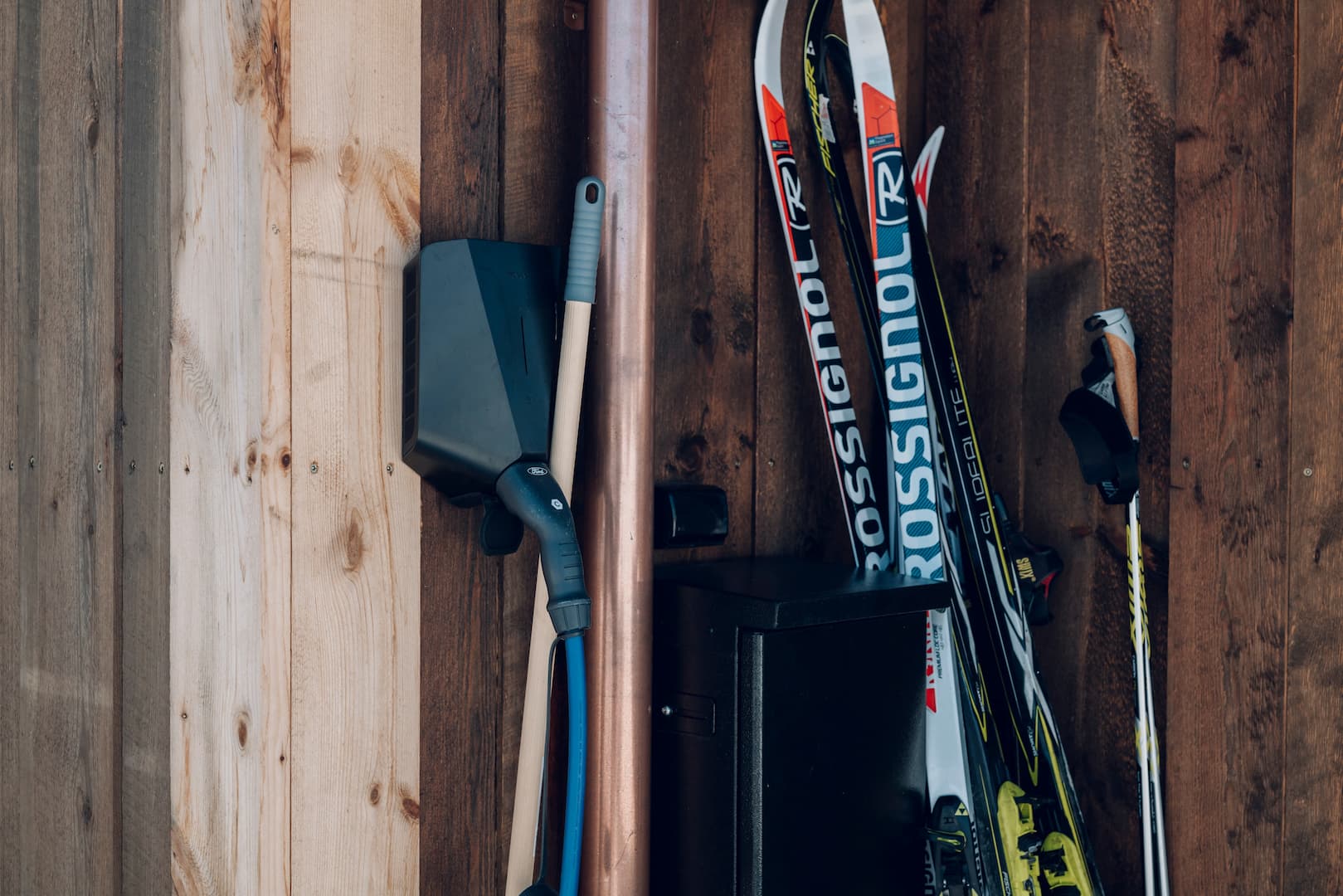 en svart elbillader på en hytte ved siden av noen ski