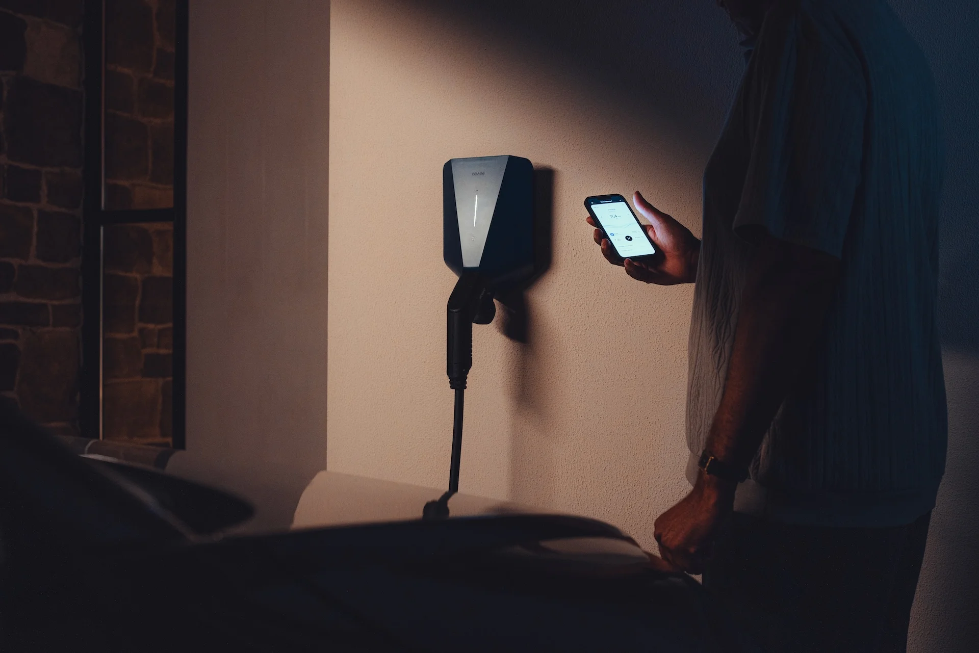A man holding his phone to control his EV charger at home